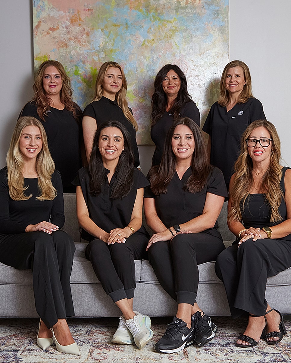 Group of women in black attire, smiling together.