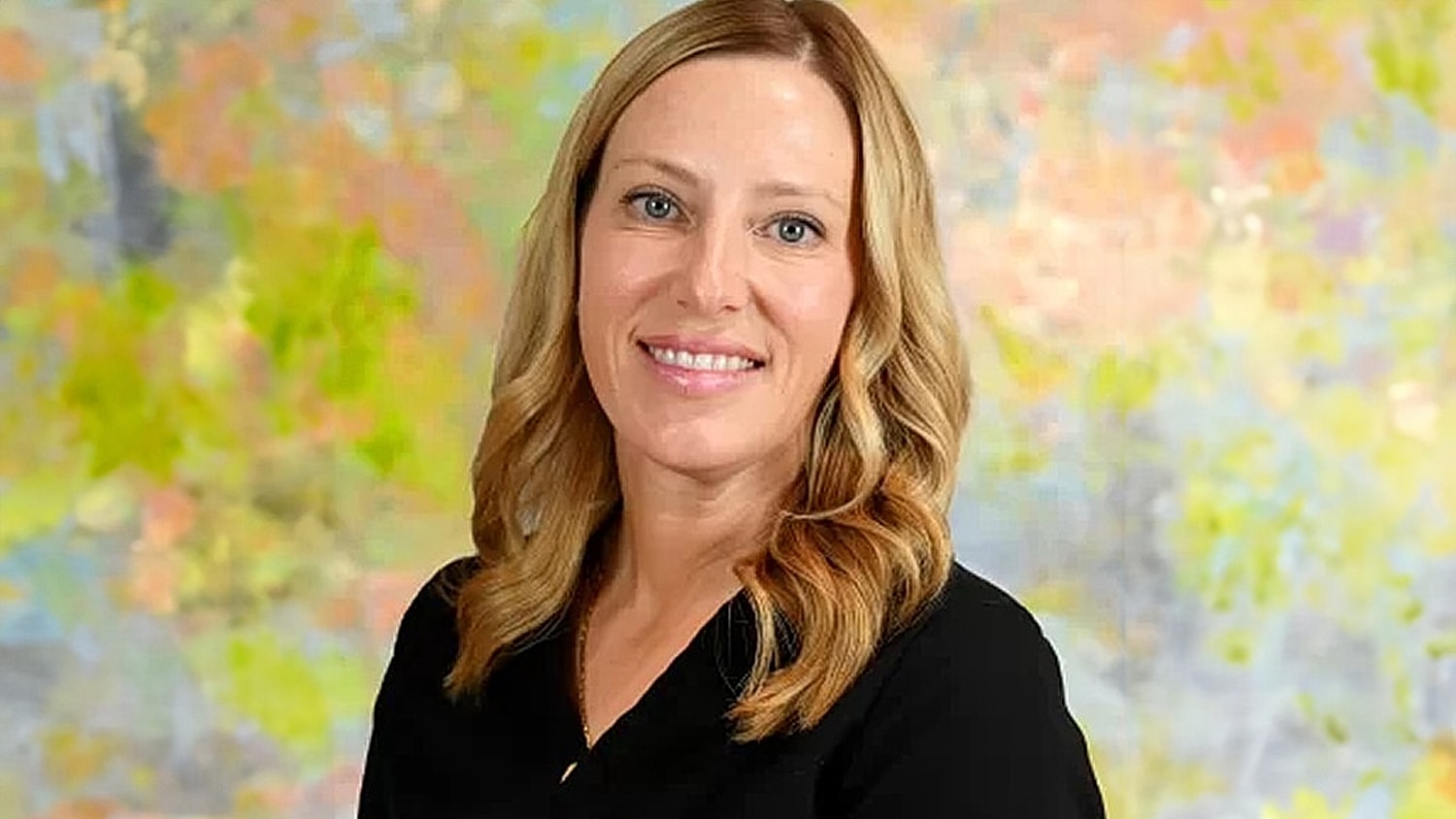 Smiling woman with wavy hair and colorful background.