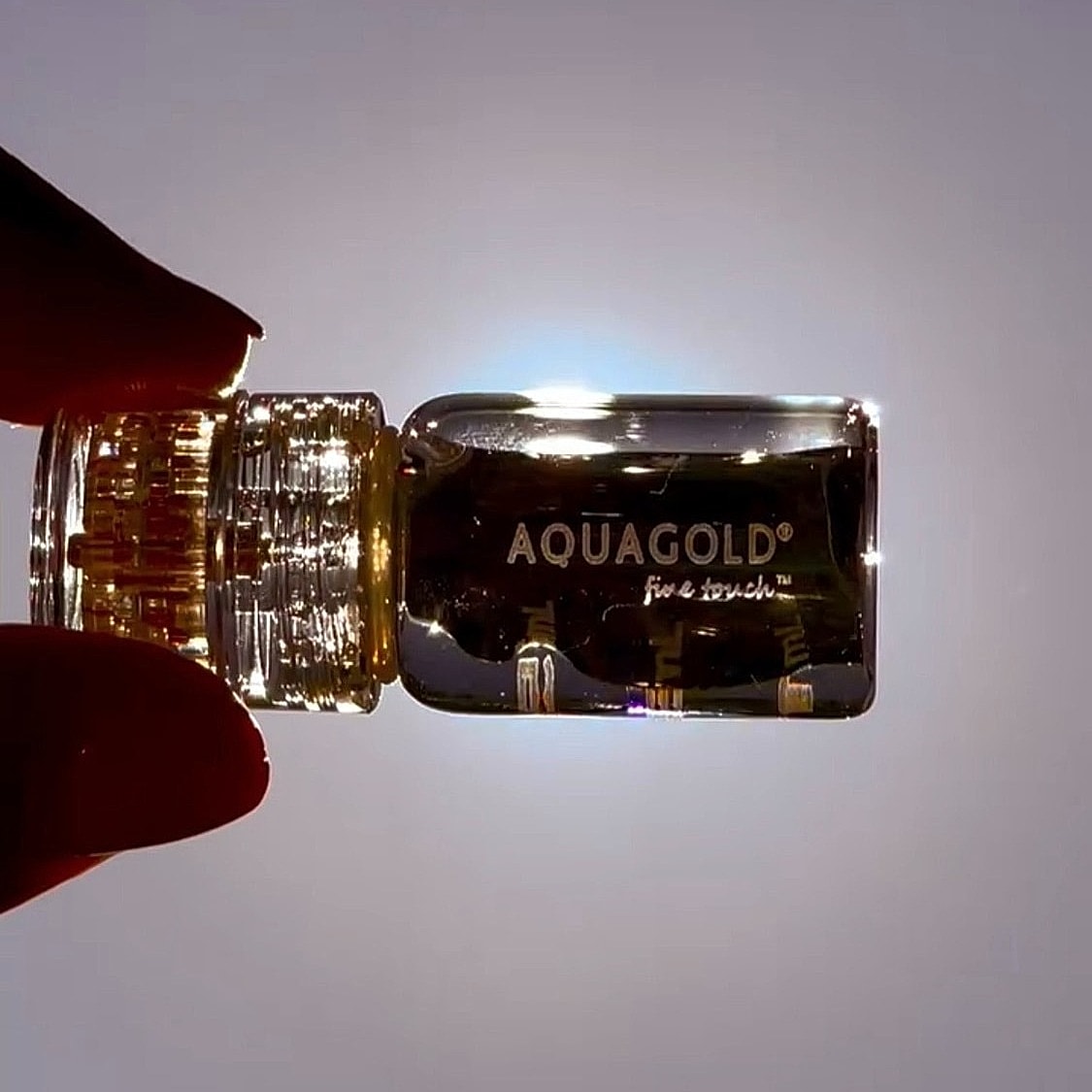 Transparent skincare vial against bright background.