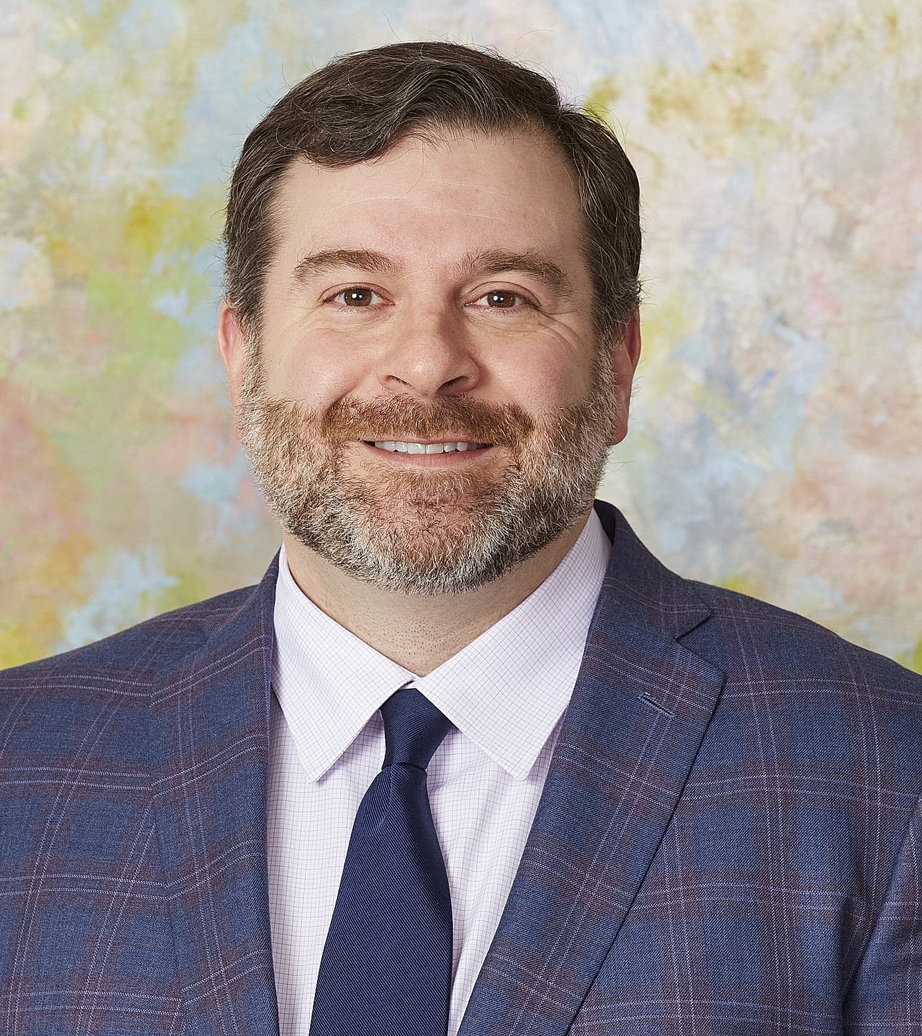 Smiling man in suit, colorful background.