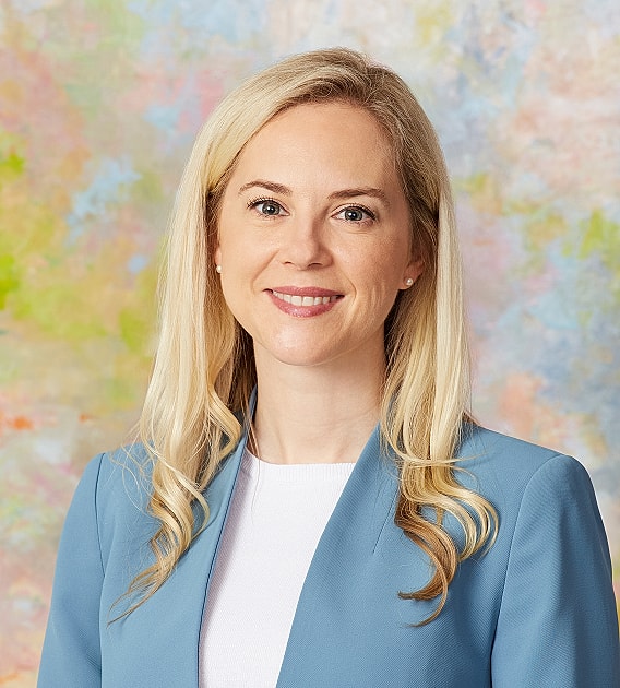Smiling woman in professional attire against colorful background.