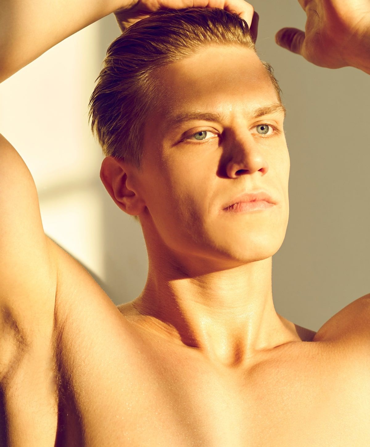 Young man posing in sunlight with serious expression.