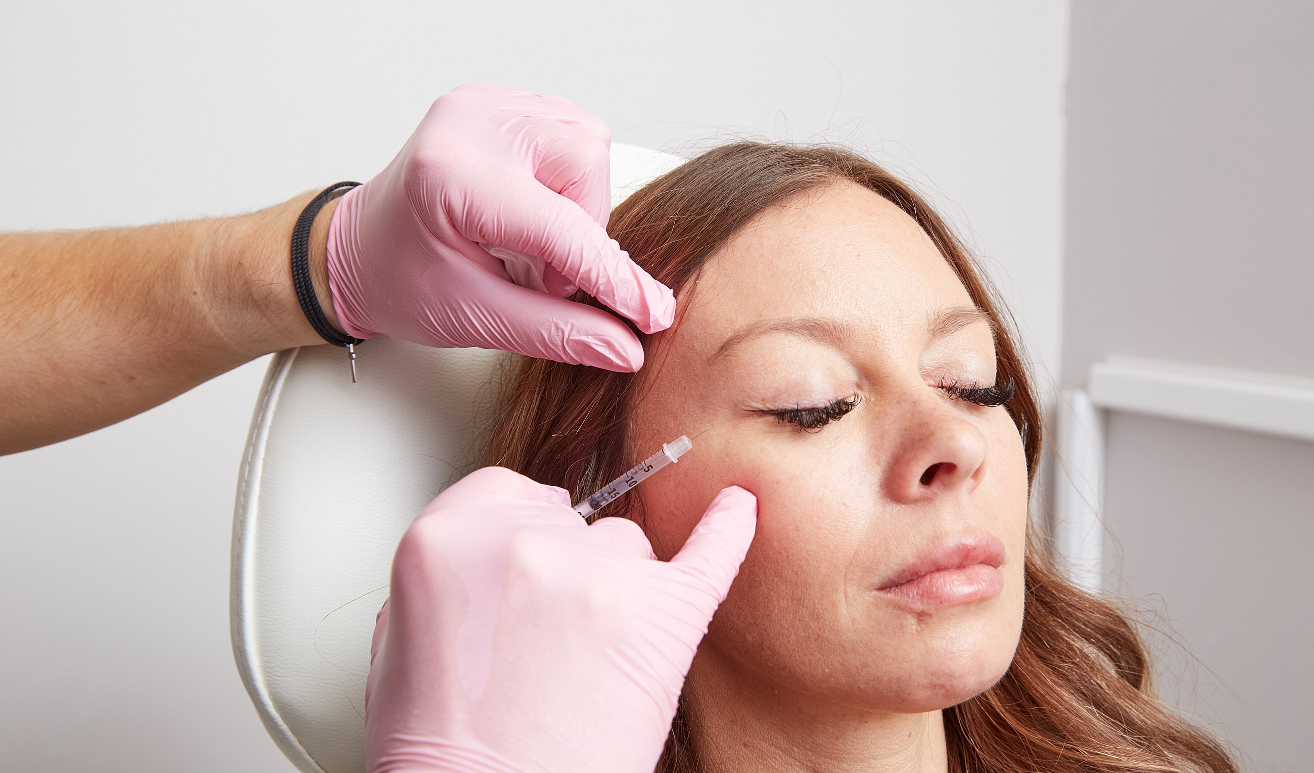 Injecting cosmetic treatment into woman's face.
