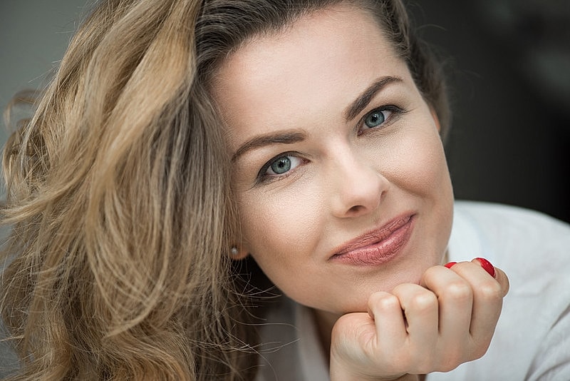 Smiling woman with wavy hair and playful expression.