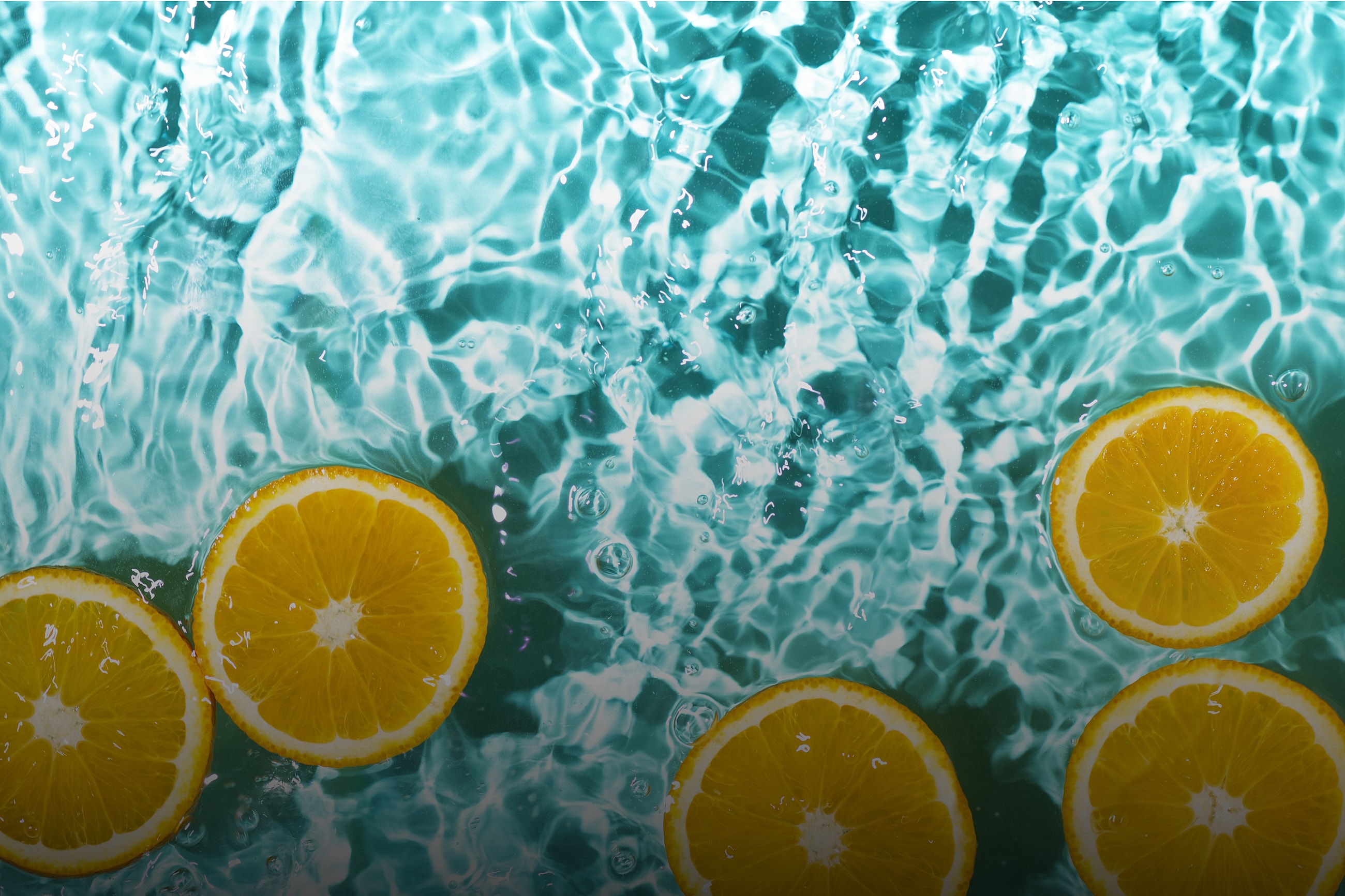 Sliced oranges floating in turquoise water.